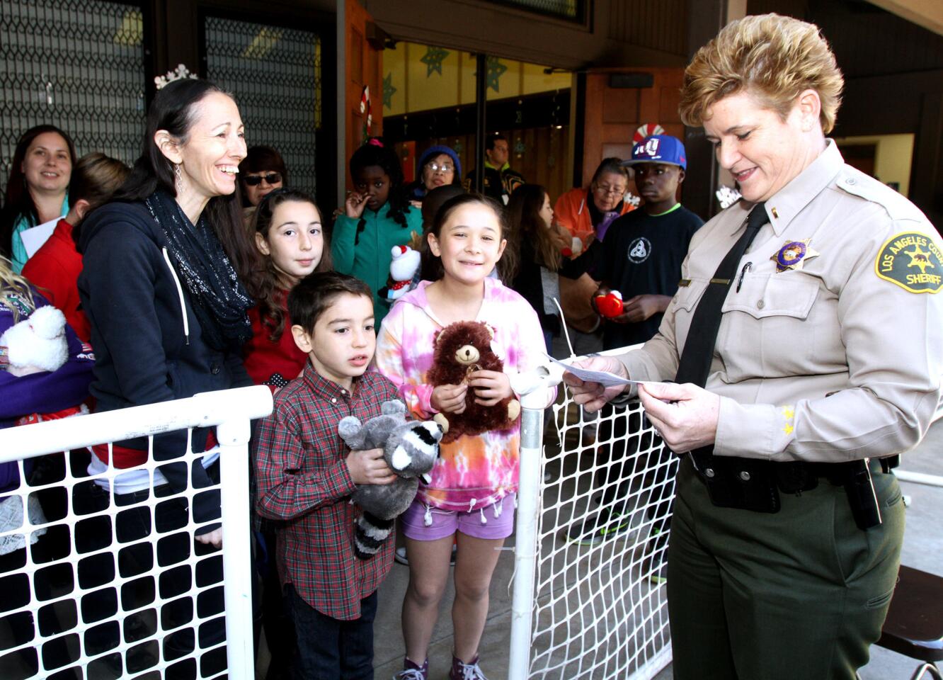 Los Angeles County Sheriff's Lt. Marjory Jacobs of the Crescenta Valley Station helps the Hill family pick out toys during the Crescenta Valley Sheriff Station's annual Toy and Food Drive at Crescenta Valley Park in La Crescenta on Saturday, Dec. 19, 2015.