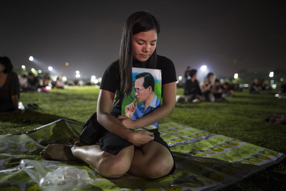 Thais pray and light candles Sunday in memory of their late king outside the Grand Palace in Bangkok, Thailand.