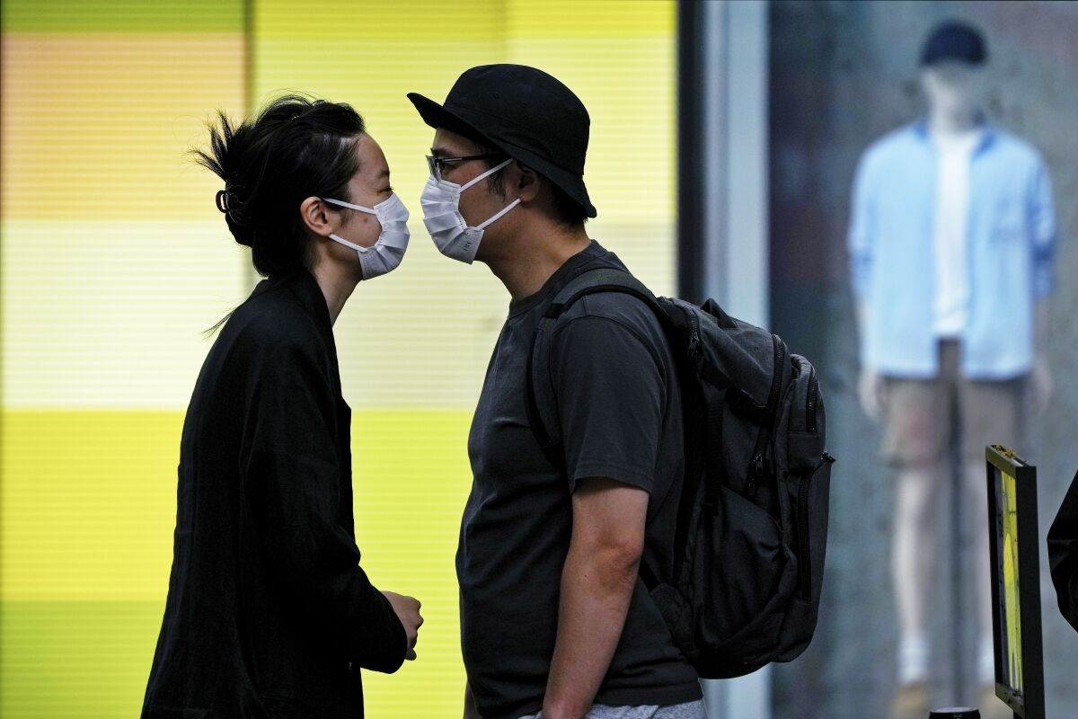A couple wearing face masks move in closer to kiss as they line up for their COVID-19 tests at a testing facility near a shopping mall where most shops have ordered to closed as part of COVID-19 controls in Beijing, Monday, June 13, 2022. China's capital has put school online in one of its major districts amid a new COVID-19 outbreak linked to a nightclub, while life has yet to return to normal in Shanghai despite the lifting of a more than two month-long lockdown. (AP Photo/Andy Wong)