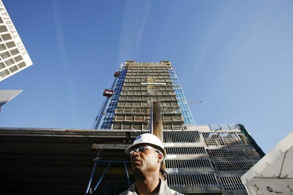 Ed Morton, a security guard at the Solair complex at Wilshire Boulevard and Western Avenue, mans his post Monday. The Wilshire corridor is one of the few areas exempt from a city law restricting the size of future high-rises.
