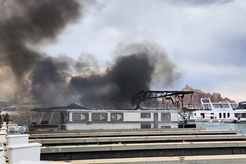 This photo provided by Robert Wilkes, owner of a house boat management company, shows smoke rising from a fire on Friday, June 2, 2023, at Wahweap Marina on Lake Powell near Page, Nev. More than half a dozen house boats momentarily caught fire at a popular boating destination on the Utah-Arizona line on Friday. (Robert Wilkes via AP)