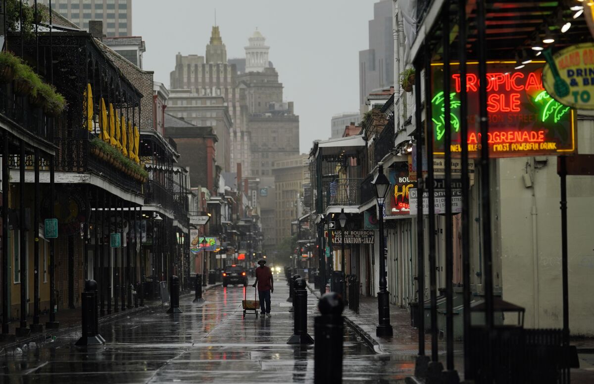 A man pulls a cart down a mostly deserted Bourbon Street in the French Quarter of New Orleans