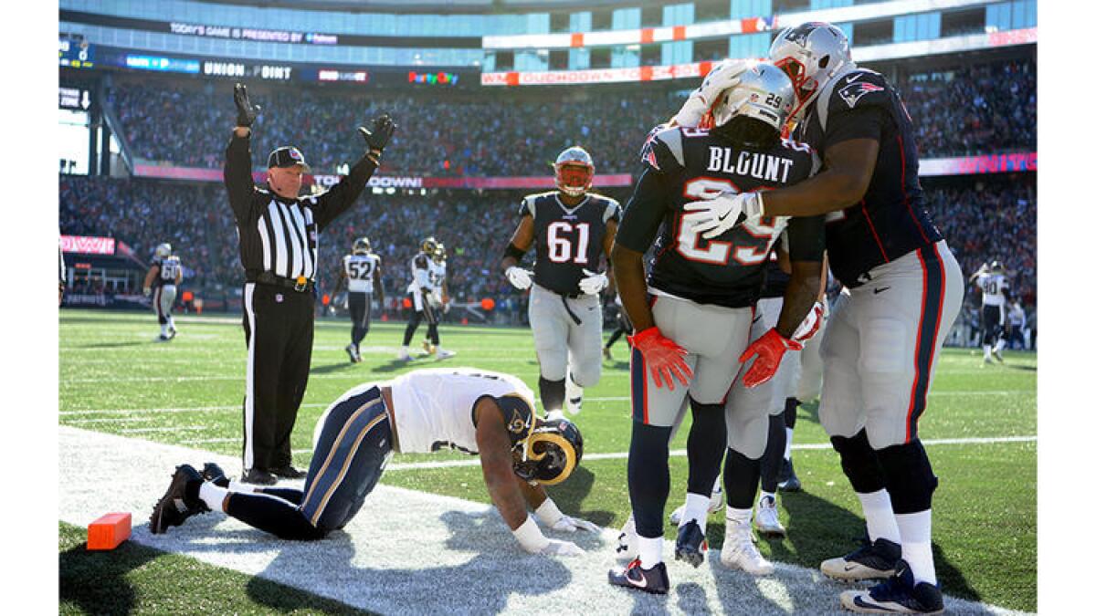 Patriots running back LeGarrette Blount is mobbed by teammates after scoring a touchdown on a 43-yard run against the Rams' Eugene Sims. To see more images from the game, click on the photo above.