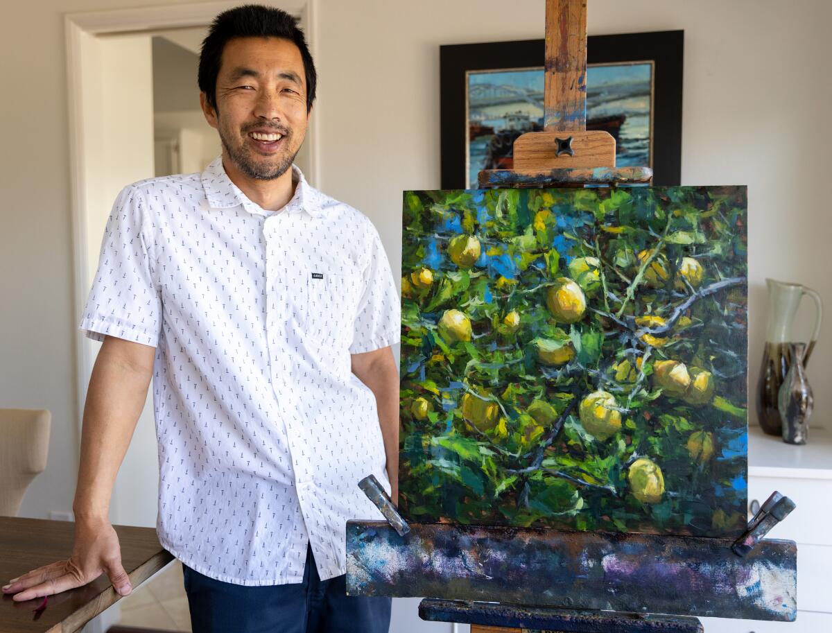 Artist Pil Ho Lee stands next to his oil painting titled "Lemon Tree No. 2," at his home in Orange on Wednesday.