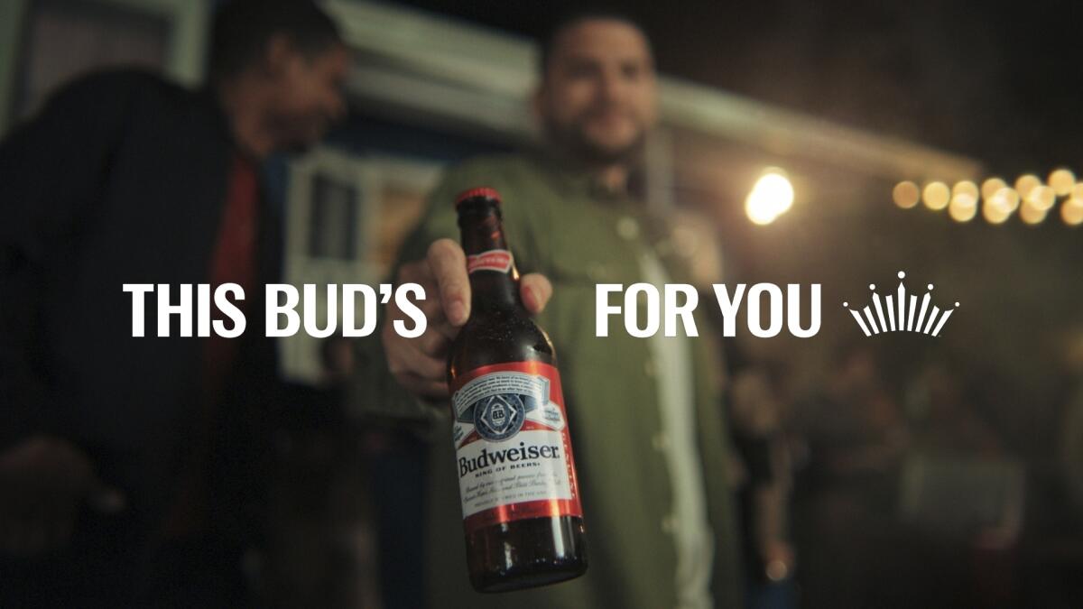 In a scene from Budweiser's 2023 Super Bowl NFL football ad, a man shows a beer bottle to the camera. 