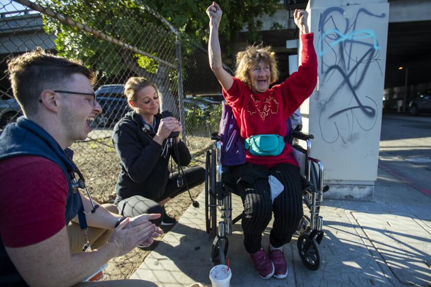 LOS ANGELES, CALIF. -- THURSDAY, DECEMBER 19, 2019: Homeless patient Dianna Hill, 61, celebrates finding out her blood pressure is lower as Dr. Michael Stefanowicz, left, and nurse Gabrielle Johnson finish checking her blood pressure of while visiting her tent she lives in next to the 10 Freeway in Los Angeles Dec. 19, 2019. Hill has been on and off homeless for 30 years and suffers from Chronic Obstructive Pulmonary Disease. The Keck School of Medicine of USC’s Street Medicine team, made up of four medical professionals, goes out every morning to provide medical care to people on the street. The team has about 70 patients who live on the street and their goal is to reduce emergency room visits for the homeless. (Allen J. Schaben / Los Angeles Times)
