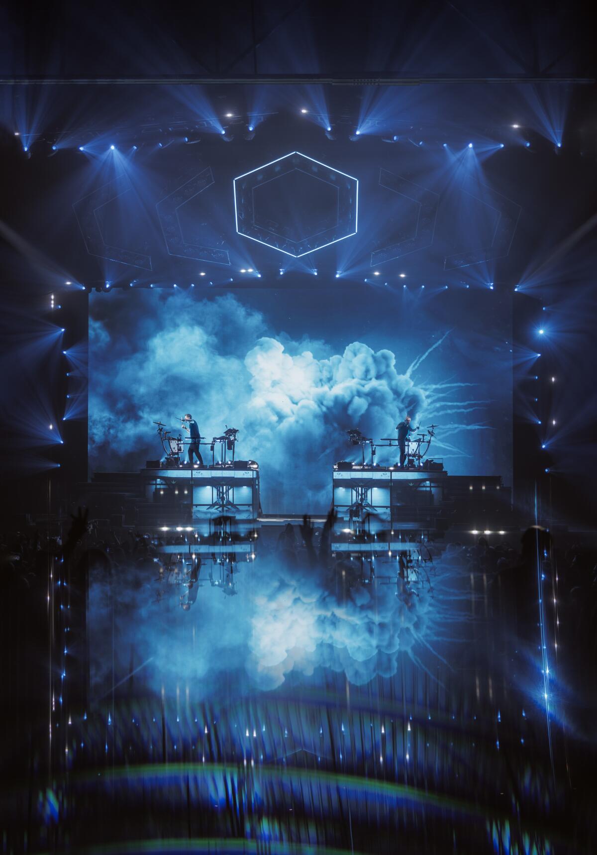 Odesza performing on a large stage surrounded by blue light