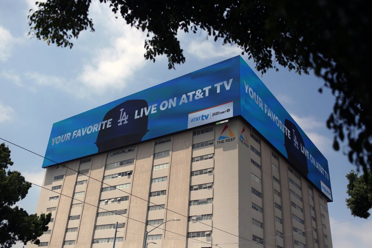 LED billboards atop a multistory building show an ad for a sports network.