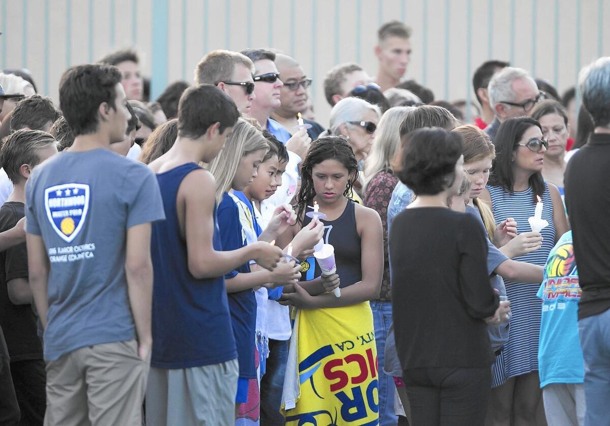 People attending a poolside vigil stand in honor of Dragon Kim and Justin Lee at Northwood High School Tuesday evening. The two teens were killed when a tree limb fell on them at Yosemite National Park.