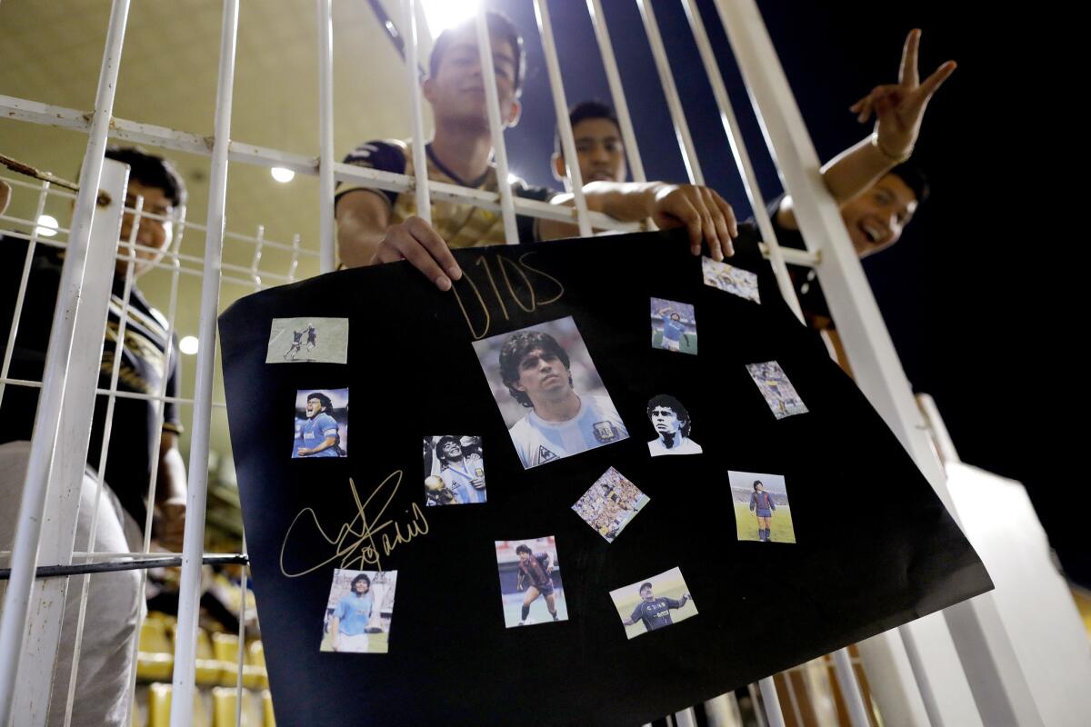 Juan Soto, 17, holds a collage of photos of Argentinian soccer legend Diego Maradona before the start of a Dorados of Sinaloa game at Estadio Banorte in Culiacán on Oct. 27.