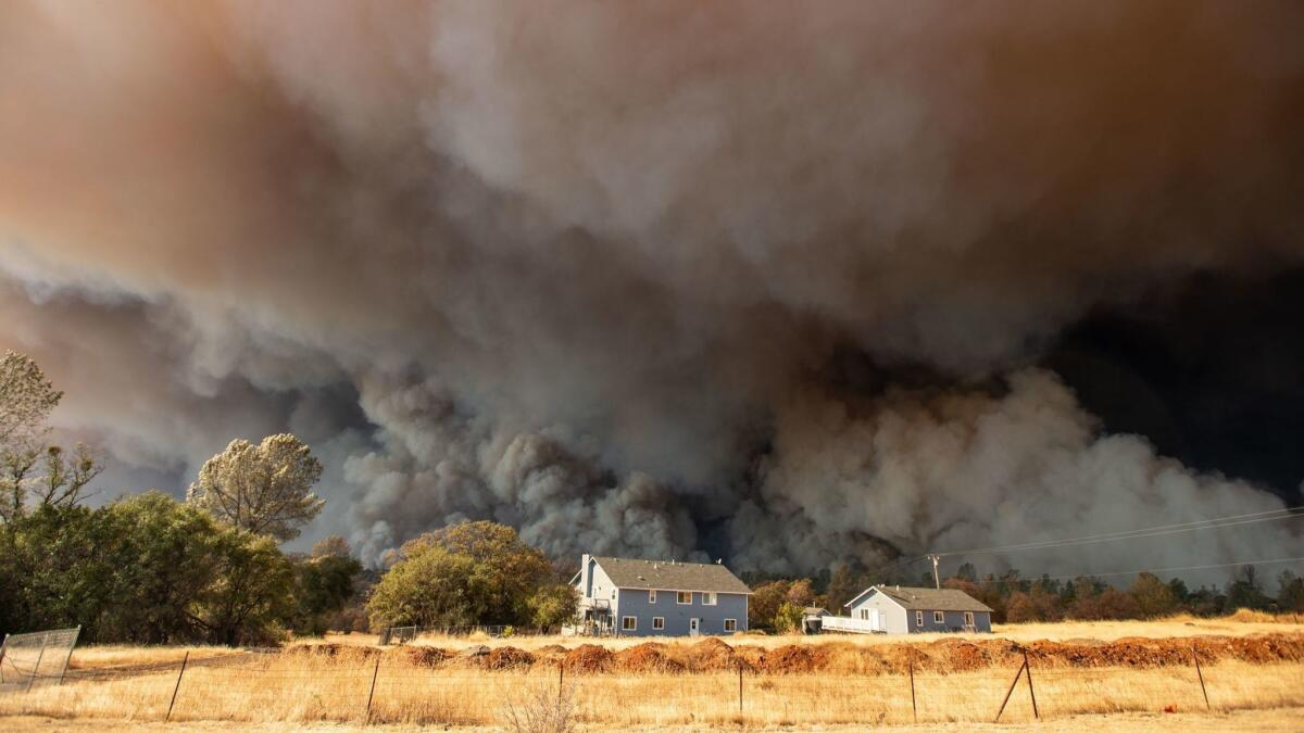 A home is overshadowed by towering smoke plumes as the Camp fire races through Paradise, Calif. Facing billions of dollars in potential liabilities over its role in a series of deadly wildfires, PG&E filed for bankruptcy protection Jan. 29.