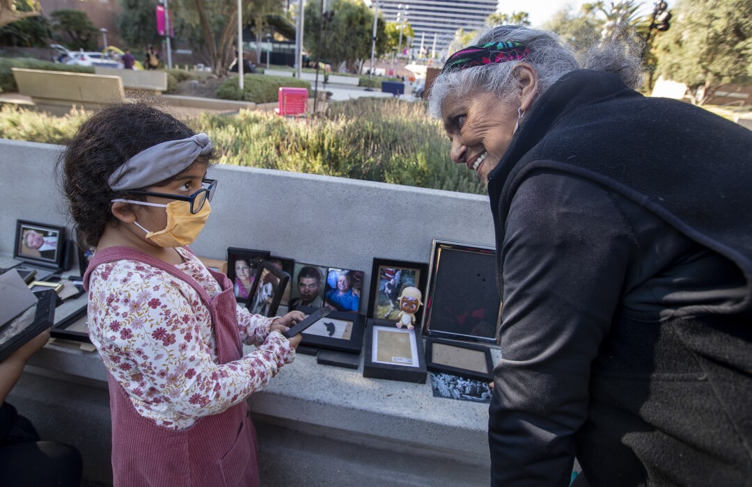 A young girl and an older woman put photos of people in frames.