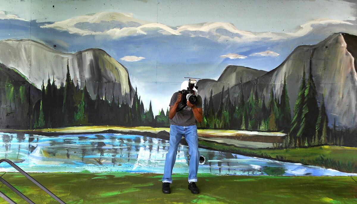 Photographer Andre Murray stands within the mural as he takes photos of the event at the unveiling of a 5,400-square-foot mural depicting Yosemite scenics similar to the photography of Ansel Adams on a corridor wall at John Muir Middle School in Burbank on Thursday, April 17, 2014. The mural, created by artist Randall Williams, took between 3 and 4 weeks with the help of students at the school.