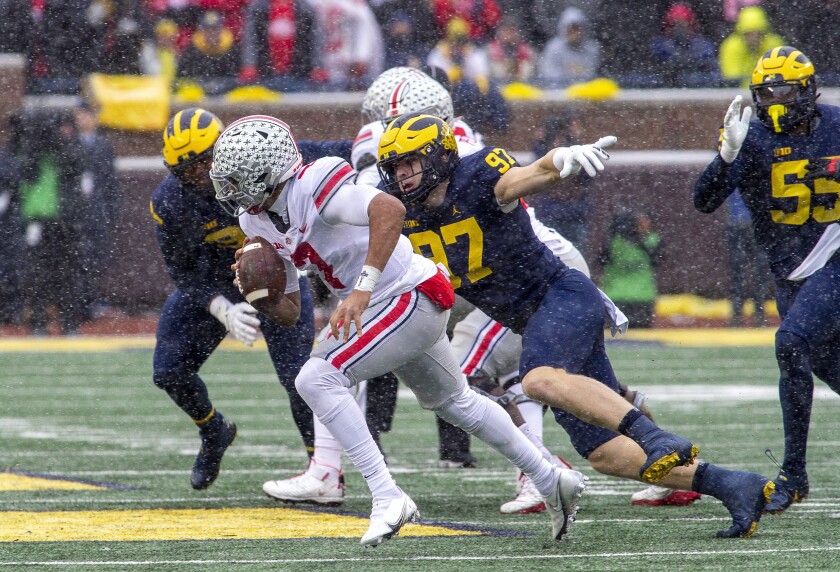 Ohio State quarterback C.J. Stroud (7) scrambles away from Michigan defensive end Aidan Hutchinson (97) in the second quarter of an NCAA college football game in Ann Arbor, Mich., Saturday, Nov. 27, 2021. Michigan coach Jim Harbaugh said star defensive end Aidan Hutchinson should be strongly considered for the Heisman Trophy after he had three sacks, setting a single-season record for college football team, in a win over Ohio State that put the Wolverines in the Big Ten championship game and national title race. (AP Photo/Tony Ding)