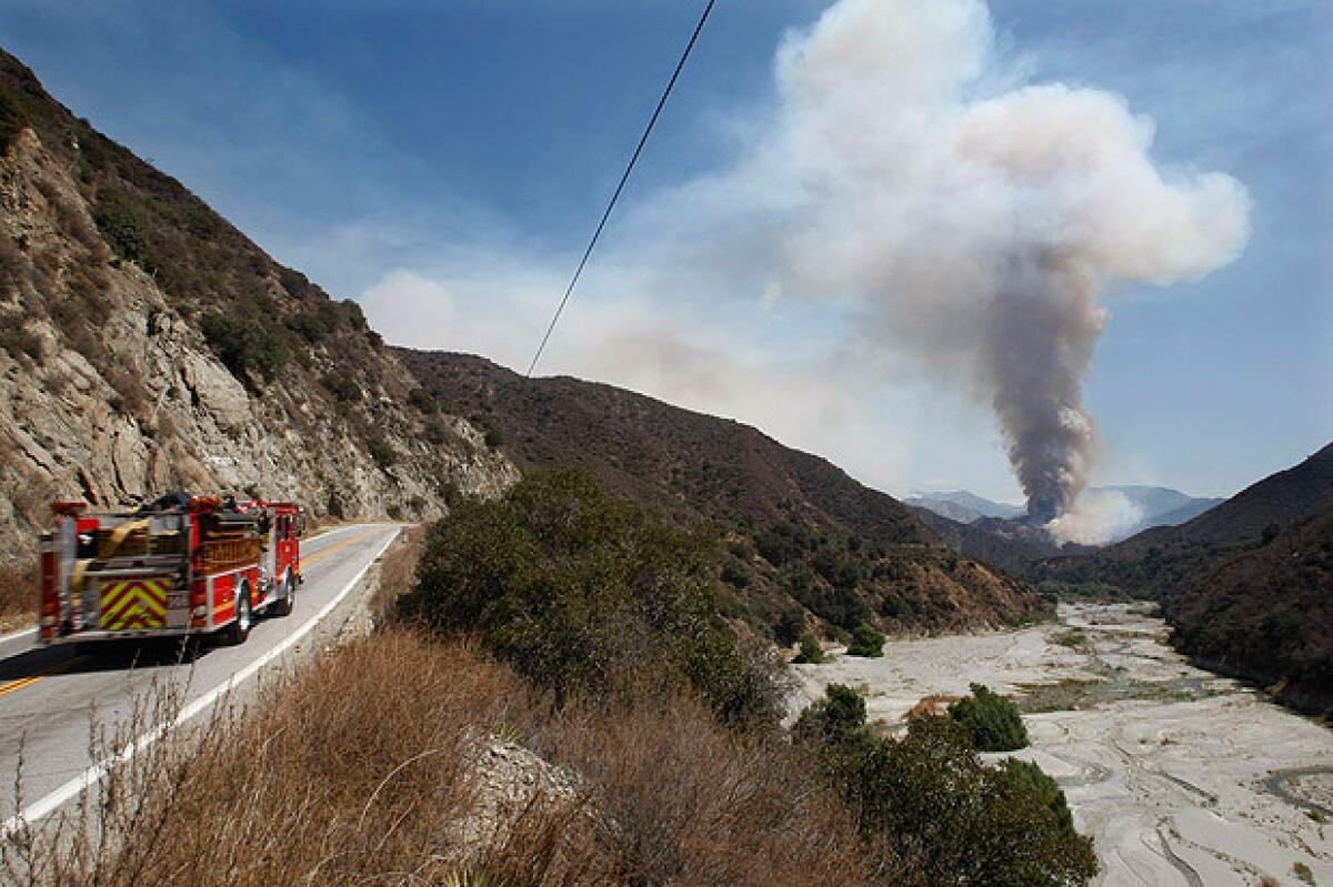 A firetruck heads north on Highway 39 toward a towering plume of smoke in Angeles National Forest near Azusa on Tuesday.