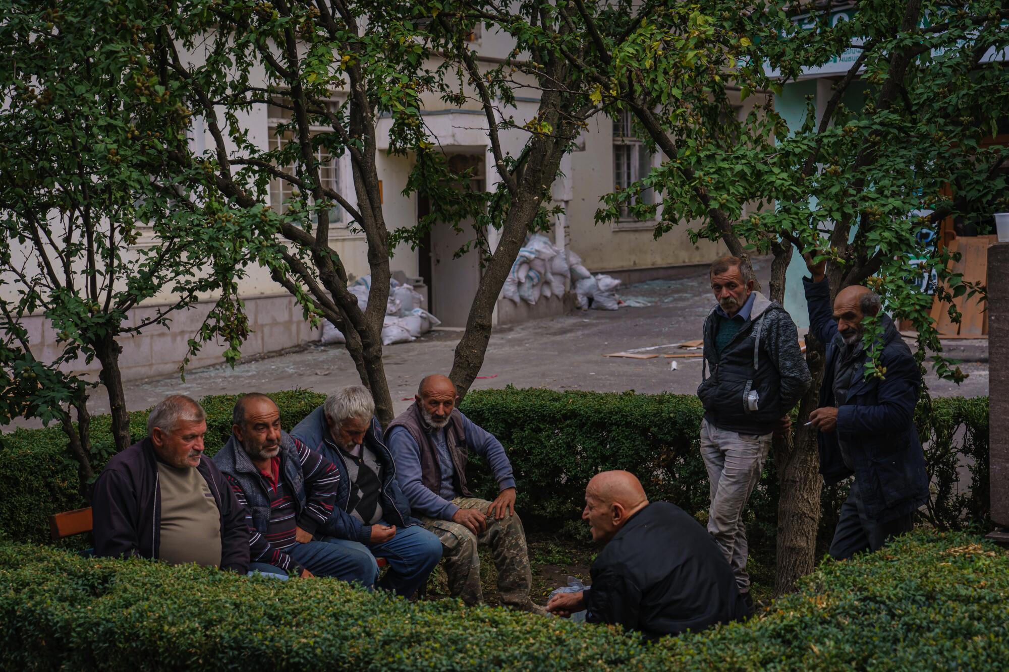 Un grupo de hombres se reúnen alrededor para fumar y charlar cerca de una compañía de telecomunicaciones en Stepanakert.