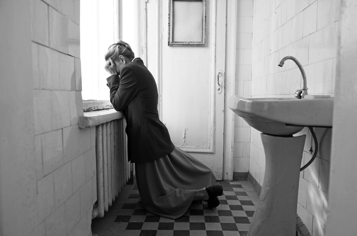 A woman weeps in despair in a bathroom.