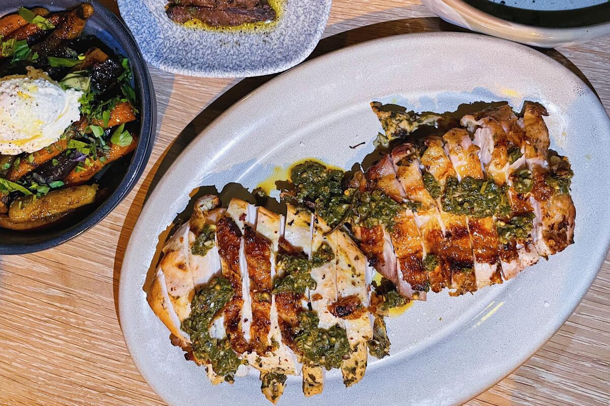 An overhead photo of a half grilled Jidori chicken with sides.