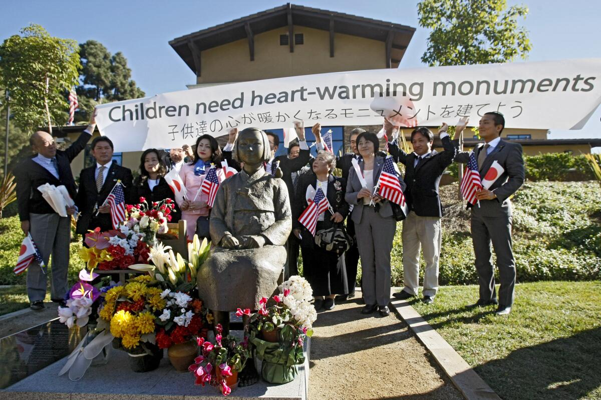 A delegation of Japanese city council members brought a sign that says "Children need heart-warming monuments" to the comfort-women statue at Central Park in Glendale on Thursday, January 16, 2014. The delegation first delivered a letter to the Glendale city clerk asking this statue be removed because they do not approve of its message.
