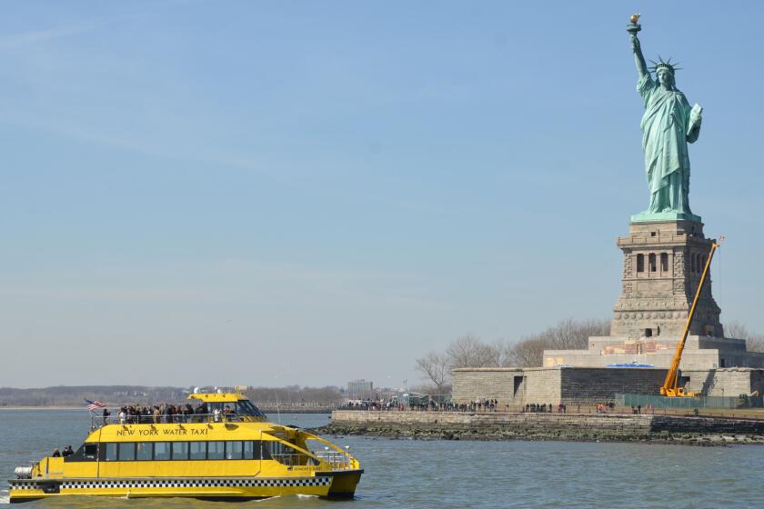 Like a Manhattanite hailing a cab, the State of Liberty towers over a New York Water Taxi.