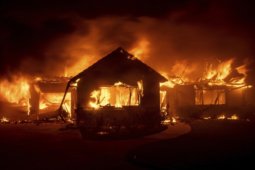 In this Oct. 31, 2019, file photo flames from the Hillside Fire consume a home in San Bernardino, Calif. 