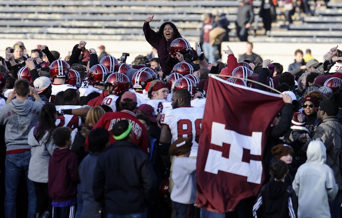 Harvard fans and players celebrate on the field after their 34-7 win over Yale at the Yale Bowl in New Haven, Conn.