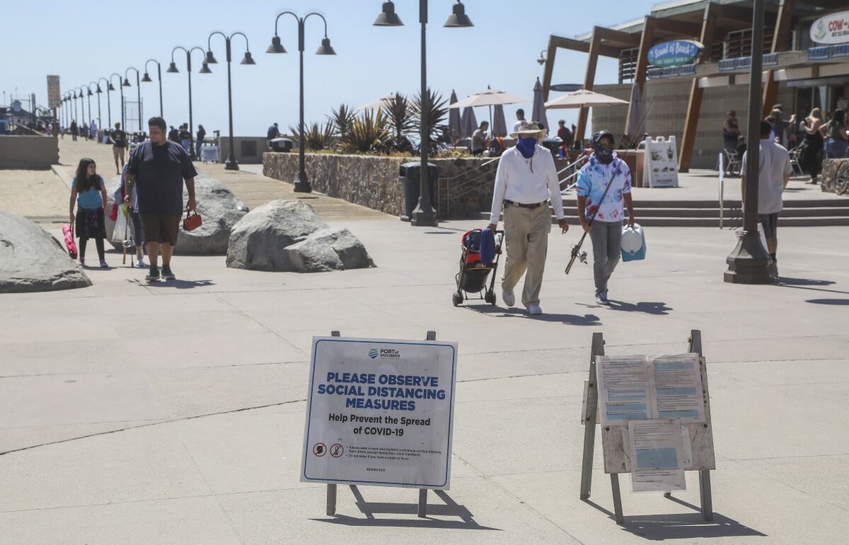 Signs posted at the entrance to the Imperial Beach Pier remind visitors about coronavirus precautions.