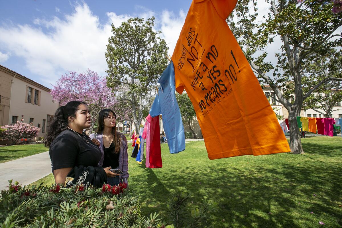 Students Emmy Gomez, left, and Cristine Phillips observe T-shirts at Fullerton College.