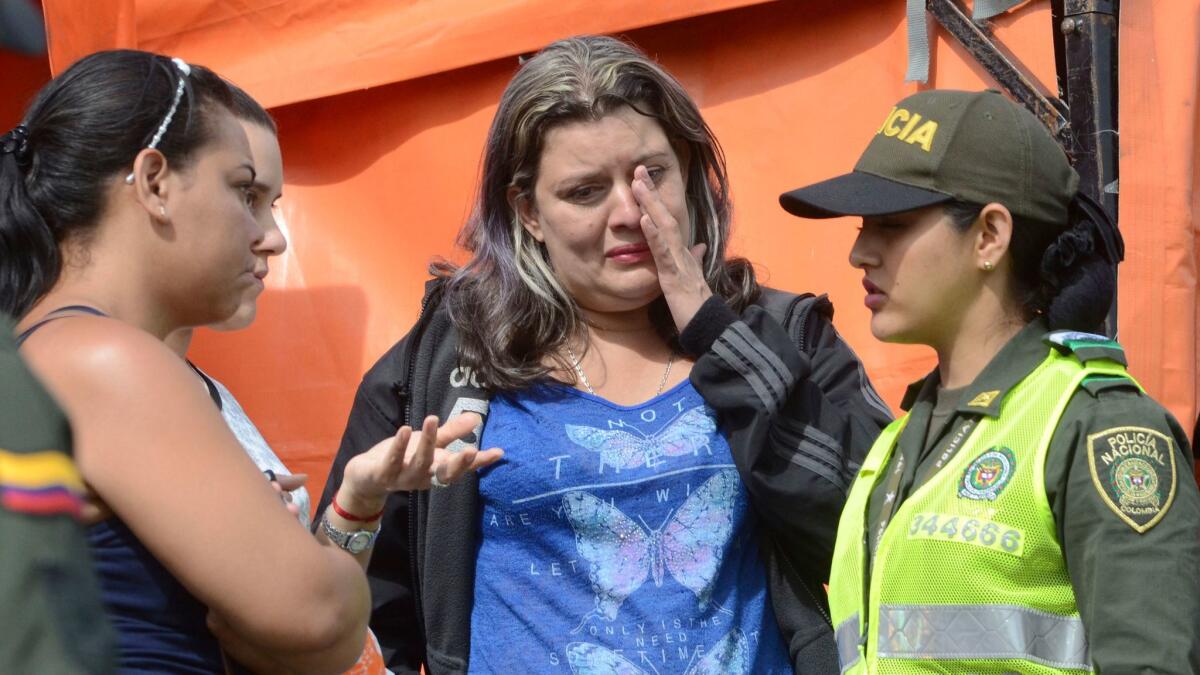 A woman wipes away tears as she waits for news on the continued search for survivors in a reservoir in Guatape, Colombia, where a tourist boat packed with passengers for the holiday weekend sank.