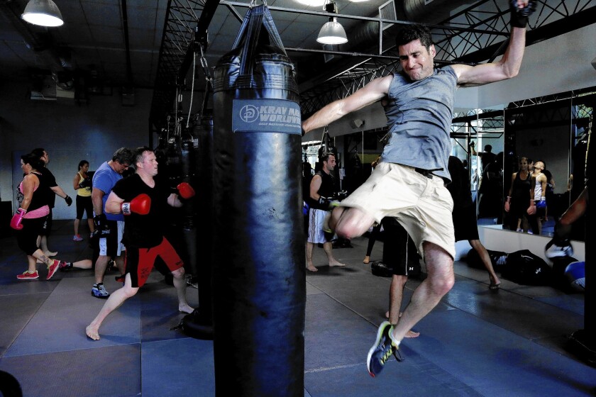 Aaron Small jumps to kick the boxing bag in a class at Krav Maga in Los Angeles.