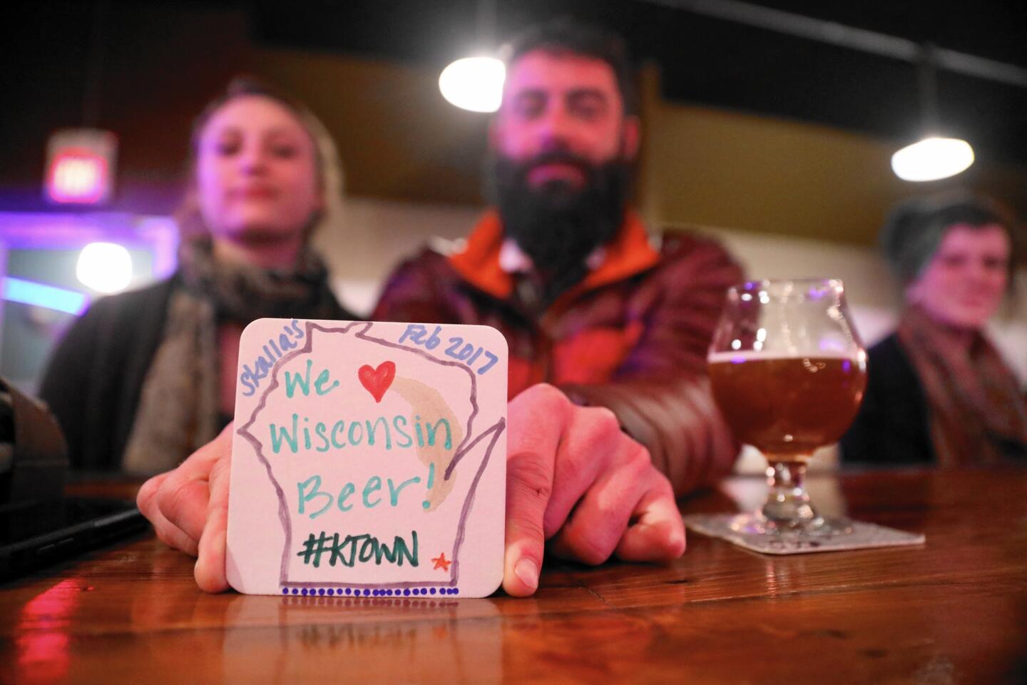 Colby Millea shows off one of the many coasters that Public Craft Brewing Co. patrons have decorated at the Kenosha, Wis., brewery.