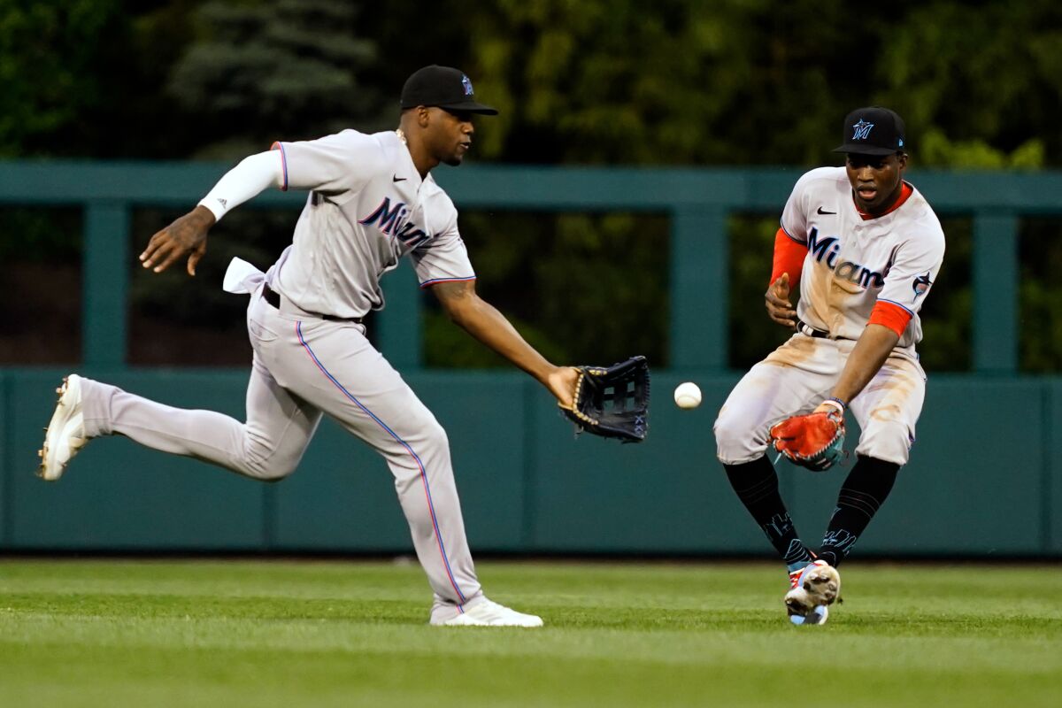 Miami Marlins' Jorge Soler, left, fields a ball hit by Philadelphia Phillies' Rhys Hoskins as Jesus Sanchez watches during the third inning of a baseball game Tuesday, June 14, 2022, in Philadelphia. (AP Photo/Matt Rourke)