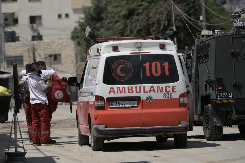 A Palestinian paramedic shows his bullet proof vest to the members of the Israeli forces inside an armoured vehicle during a military operation in the West Bank city of Jenin, Wednesday, Aug. 28, 2024. (AP Photo/Majdi Mohammed)