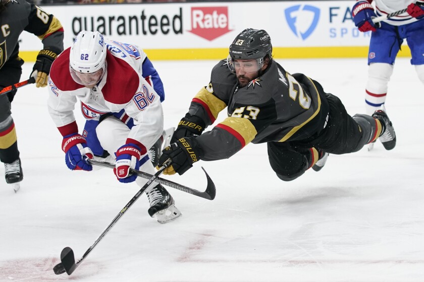 Vegas Golden Knights defenseman Alec Martinez (23) lunges for the puck next to Montreal Canadiens left wing Artturi Lehkonen (62) during the second period in Game 2 of an NHL hockey Stanley Cup semifinal playoff series, Wednesday, June 16, 2021, in Las Vegas. (AP Photo/John Locher)