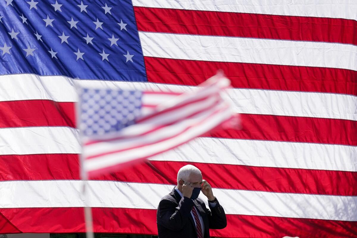 Vice President Mike Pence removes his face covering as he walks on stage prior to a campaign rally in Arizona.