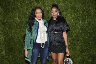 Angela Simmons, left, and Keke Palmer posing together in front of green backdrop. 