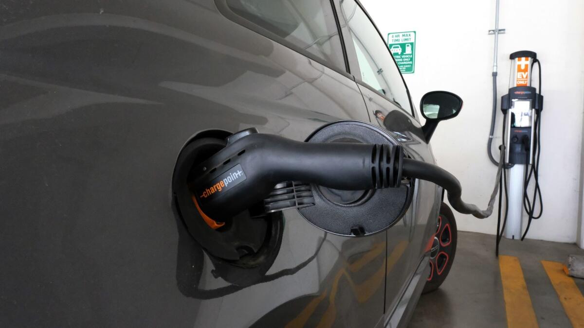 An electric Fiat is plugged into a charging station in a parking lot in Los Angeles.