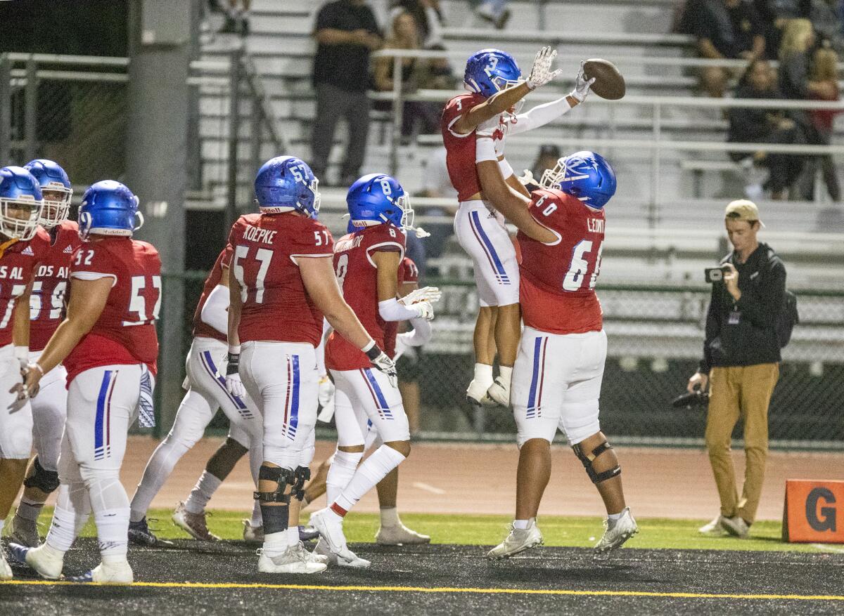 Los Alamitos' Alfonzo Leomiti (60) lifts Gavin Porch after he scores a touchdown during a Sunset League game against CdM.