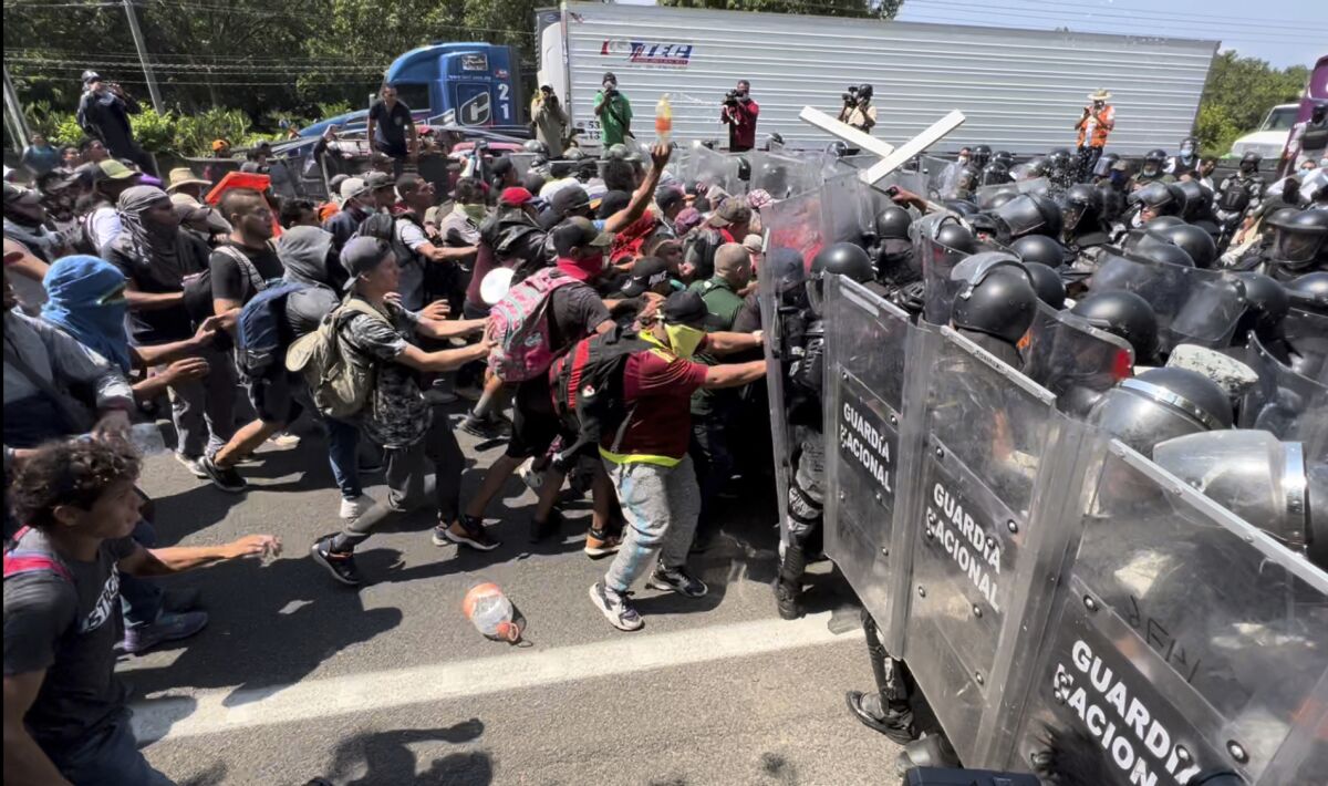 Migrant break through a line of National Guards trying to block them from leaving Tapachula, Mexico, Friday, April 1, 2022. Migrants have complained they have been essentially confined to Tapachula by the slow processing of their asylum cases and that they are unable to find work. (AP Photo/Edgar H. Clemente)