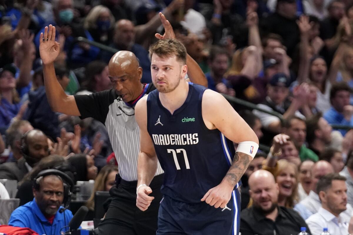 Dallas Mavericks guard Luka Doncic (77) runs upcourt as referee Leon Wood, left, signals Doncic's 3-point basket during the second half of the team's NBA basketball game against the Portland Trail Blazers, Friday, April 8, 2022, in Dallas. (AP Photo/Tony Gutierrez)