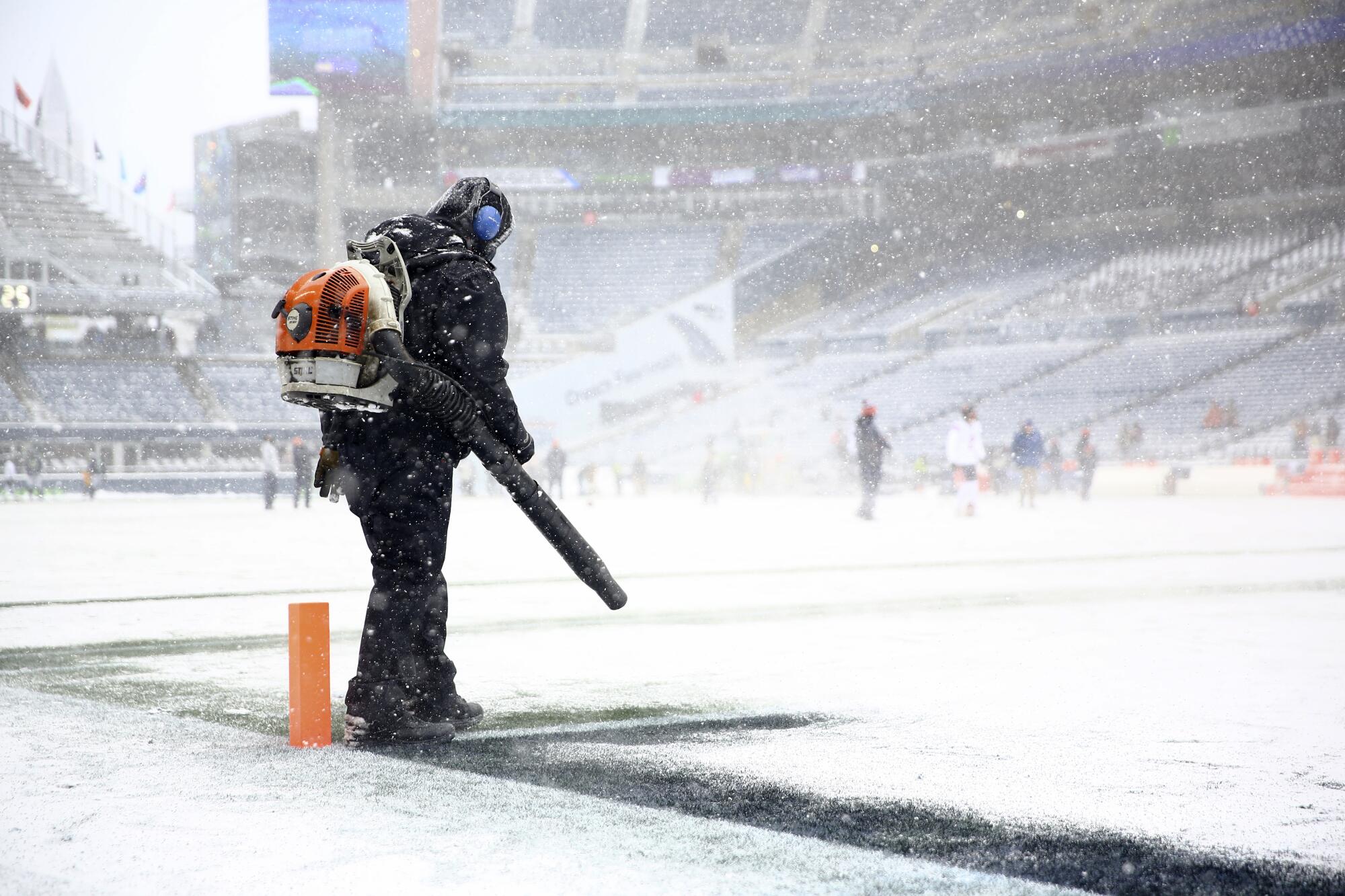 A worker clears snow from an end zone line with a blower in Chicago.