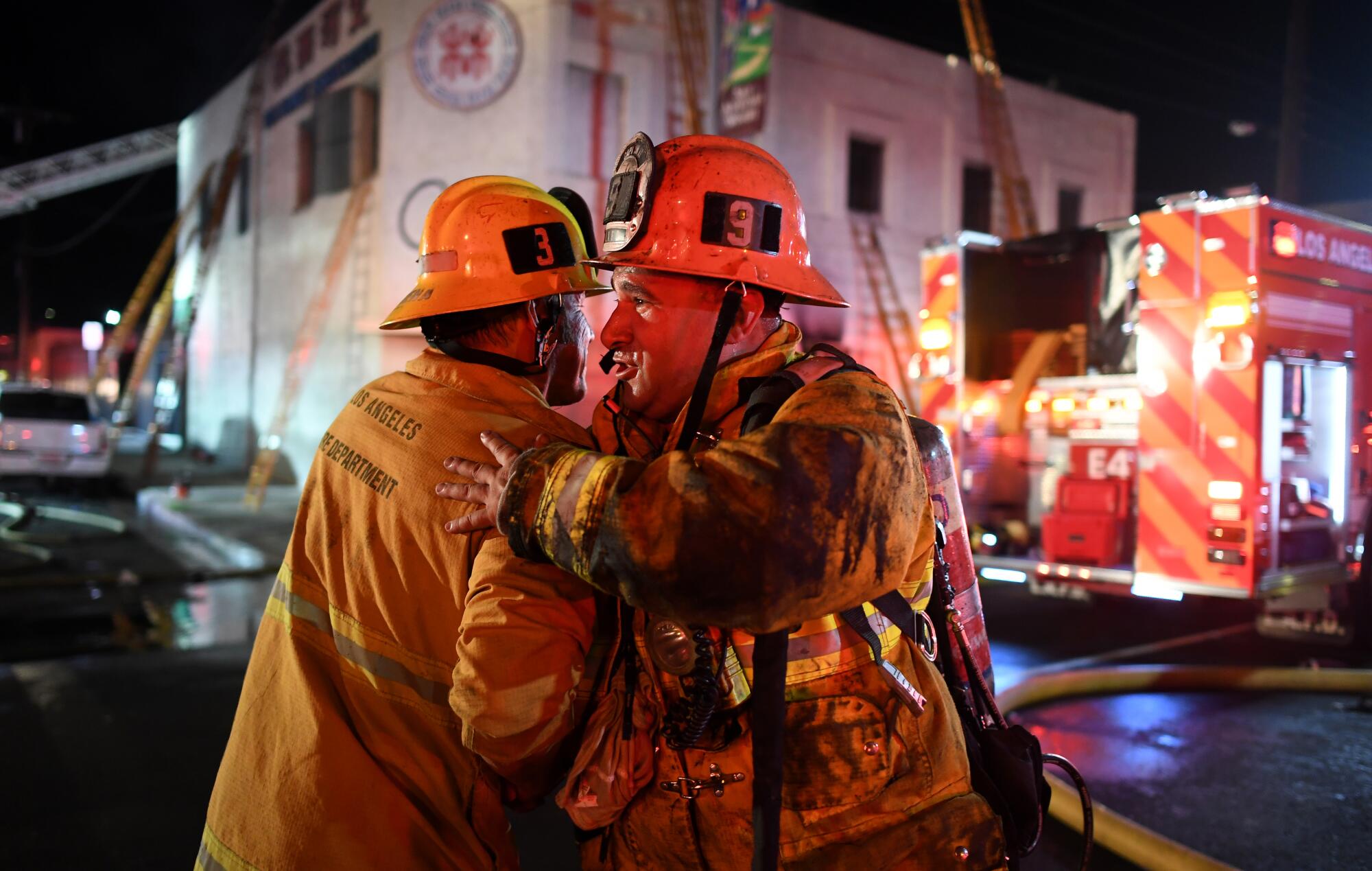 Station No. 9 firefighter Ray Robles, right, hugs a comrade after battling a predawn fire in downtown Los Angeles