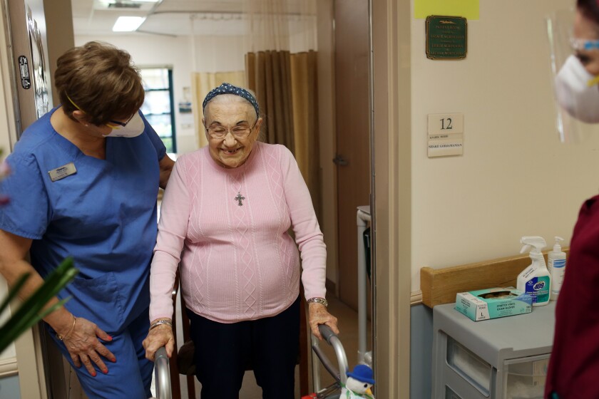 A nurse walking with an elderly resident using a walker