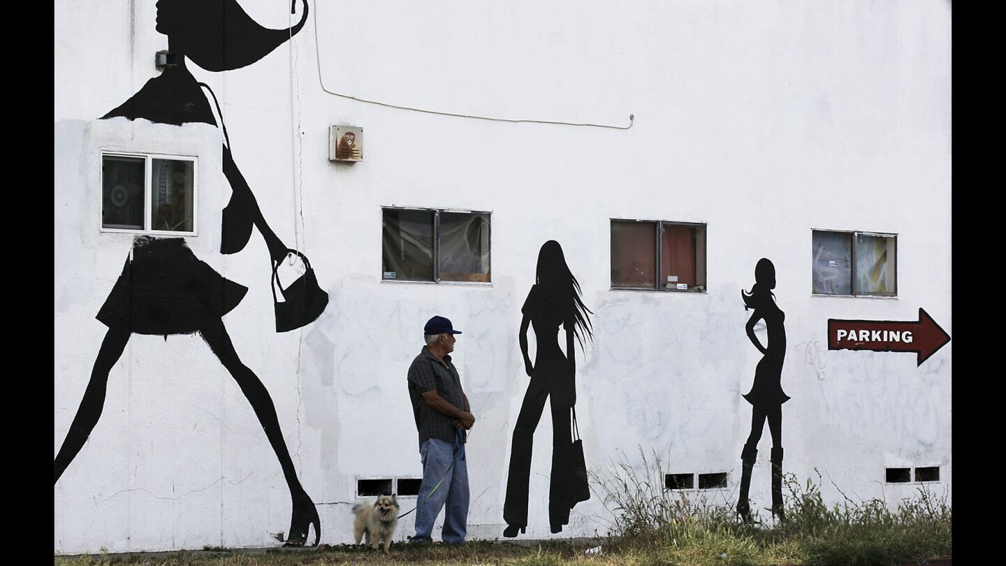 A man walks a dog along Hoover Street in South Los Angeles.