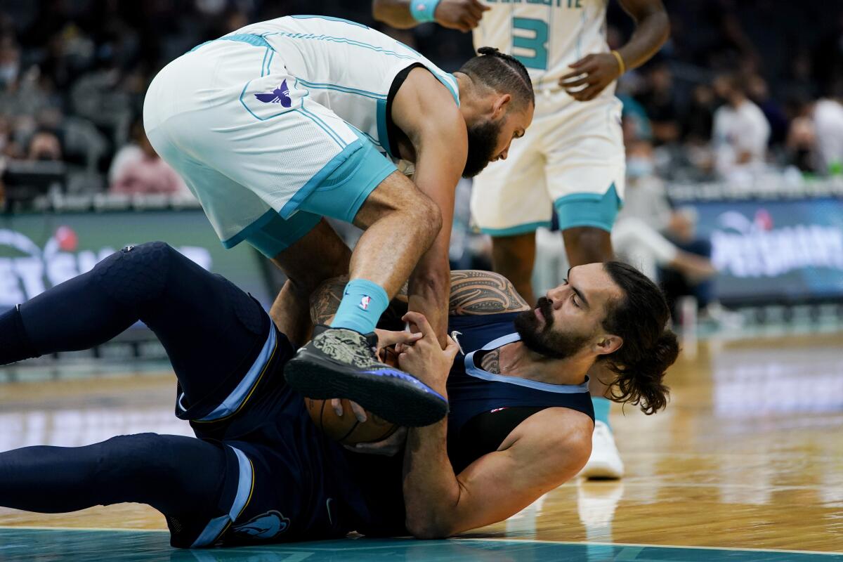 Charlotte Hornets forward Cody Martin and Memphis Grizzlies' Steven Adams struggle to get possession of the ball during the first half of a preseason NBA basketball game Thursday, Oct. 7, 2021, in Charlotte, N.C. (AP Photo/Chris Carlson)