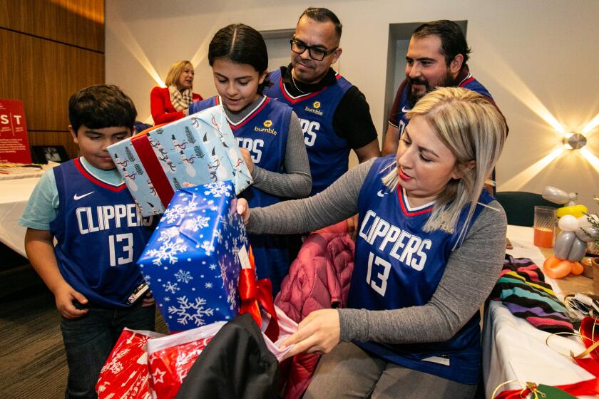 Los Angeles, CA., December 18, 2019: The Rios family opens gifts from LA Clippers star Paul George at his third annual Christmas Celebration at Dave and Busters on Wednesday, December 18, 2019 in Los Angeles, California. The Paul George Foundation has partnered with the American Stroke Association to bring families impacted by stroke together for a fun filled evening. (Jason Armond / Los Angeles Times)