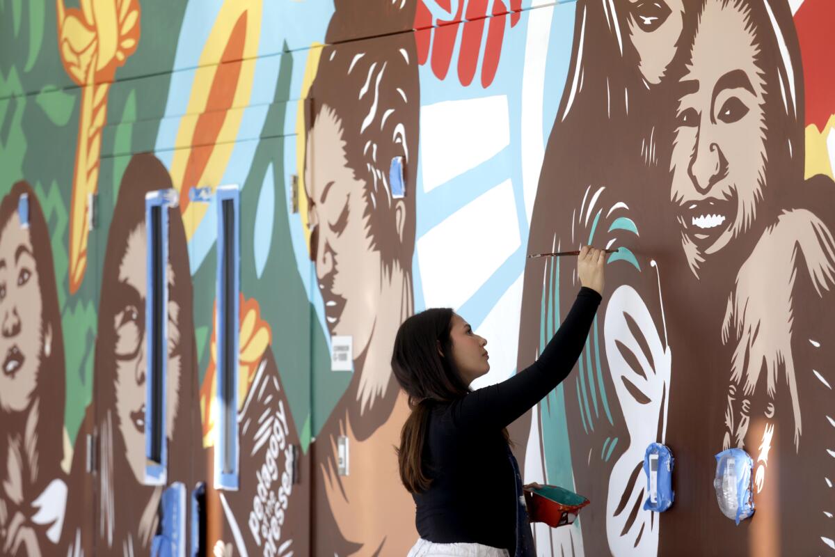 Ione Aceves works on a mural