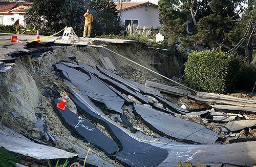 A firefighter looks over the sinkhole in Soledad Mountain Road on Wednesday near La Jolla. The sinkhole and slide damaged dozens of houses and caused the temporary evacuation of dozens more.