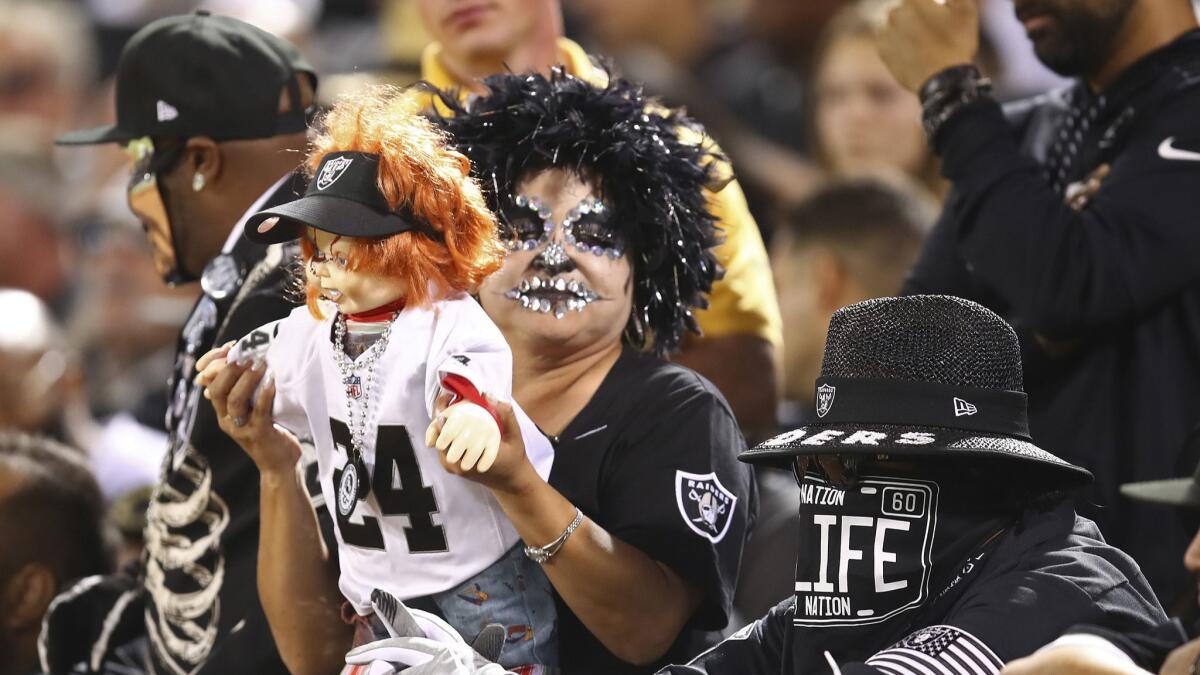 An Oakland Raiders fan holds a Chucky doll.