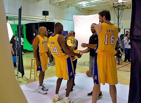 Lakers starters Derek Fisher, Kobe Bryant and Pau Gasol prepare for a photo shoot with the NBA championship trophy during media day on Saturday at the Toyota Sports Center in El Segundo.